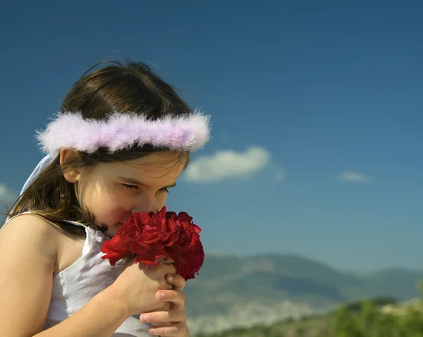 Κορίτσι μυρίζοντας κόκκινα τριαντάφυλλα — Φωτογραφία Αρχείου