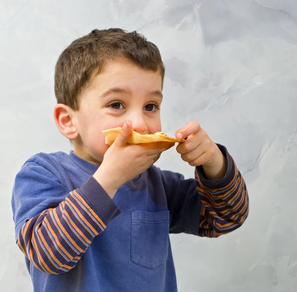 Ung pojke äter pizza — Stockfoto