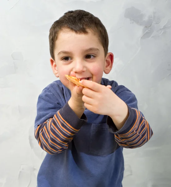 Ung pojke äter pizza — Stockfoto