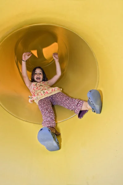 Menina em um diapositivo de playground — Fotografia de Stock
