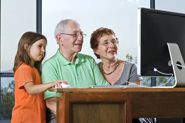 Grandparents and granddaughter with computer — Stock Photo, Image