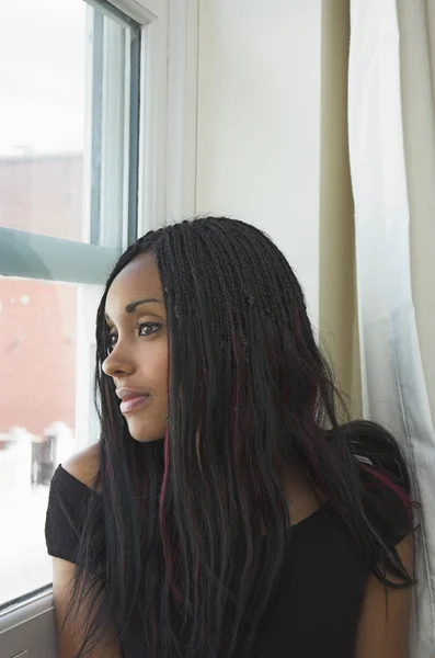 Beautiful black woman gazing out of window — Stock Photo, Image