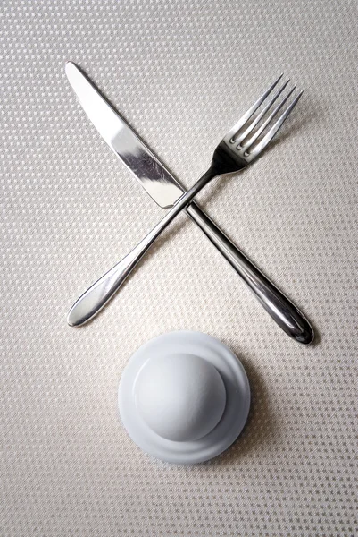 Um ovo com faca cruzada e garfo — Fotografia de Stock