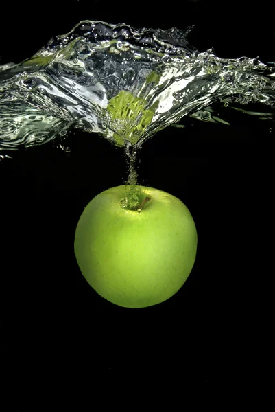 Green apple dropped into water — Stock Photo, Image