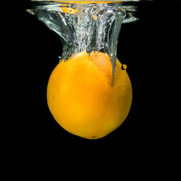 Orange dropped into water on black — Stock Photo, Image