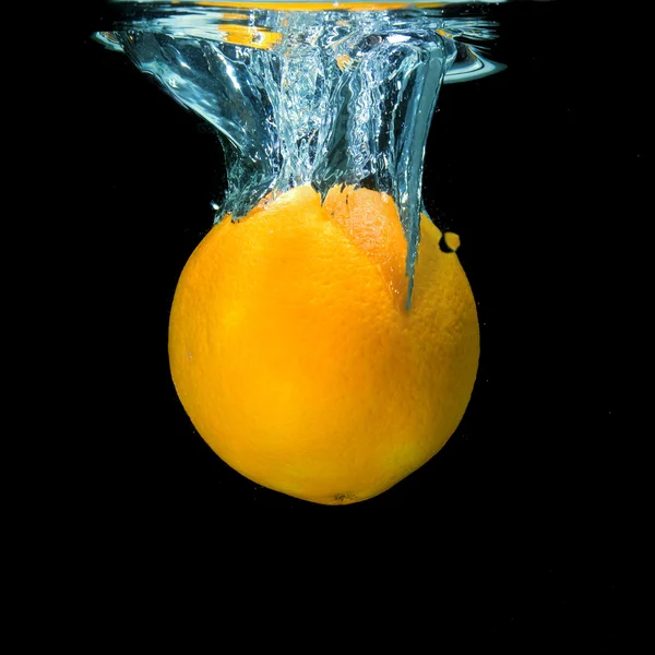 Naranja caído en el agua en negro — Foto de Stock