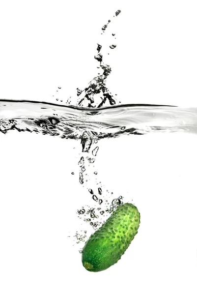 Groene komkommers gedaald in water — Stockfoto