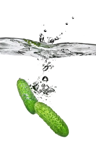 Green cucumbers dropped into water — Stock Photo, Image