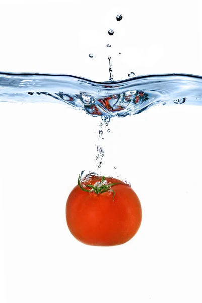 Rode tomaten gedaald in water — Stockfoto