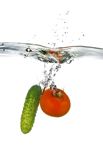 Rode tomaten en groene komkommer in water — Stockfoto