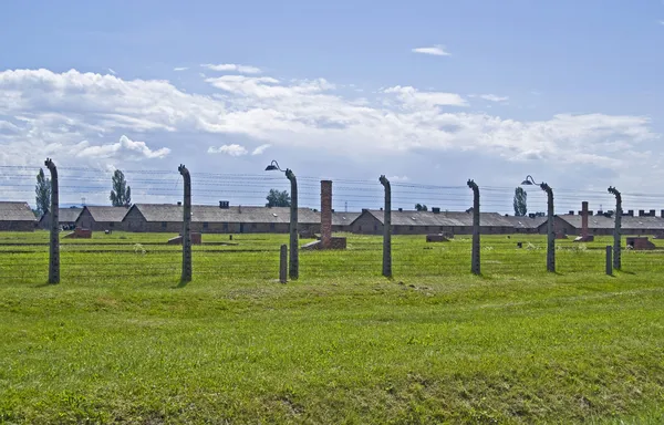 Проволочный забор и казармы Биркенау — стоковое фото