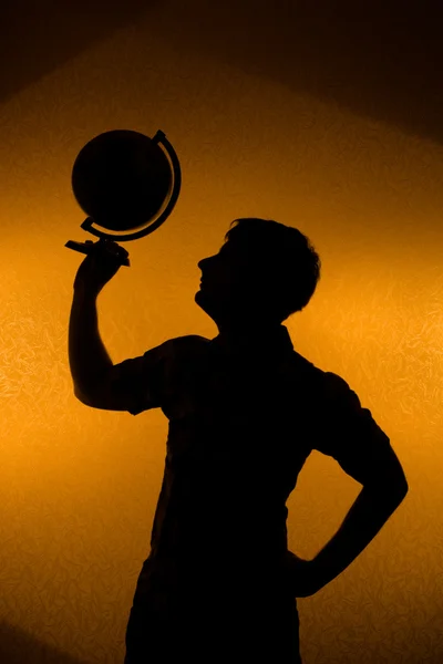 Zadní světlo - siluetu člověka drží glóbus — Stock fotografie