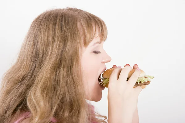 The girl bites a hamburger — Stock Photo, Image