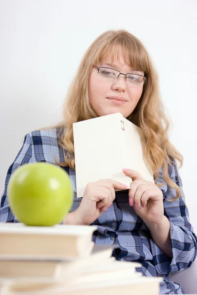 A menina com o livro olha para uma maçã — Fotografia de Stock