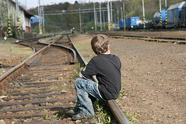 Boy sitting on rail track — Stock Photo, Image