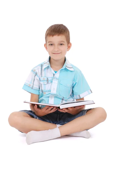 Mladý chlapec sedí blízko otevřená kniha — Stock fotografie