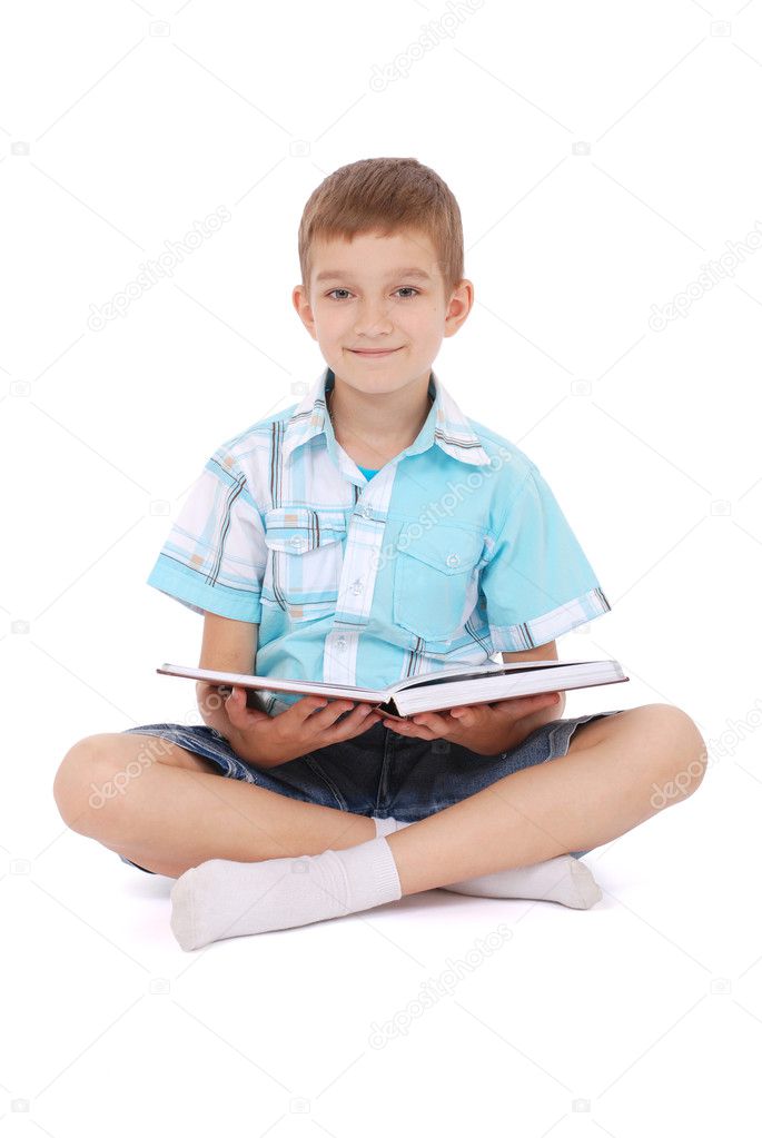 The young boy sits near the open book