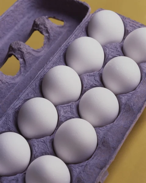 Дюжина яиц на жёлтом фоне — стоковое фото