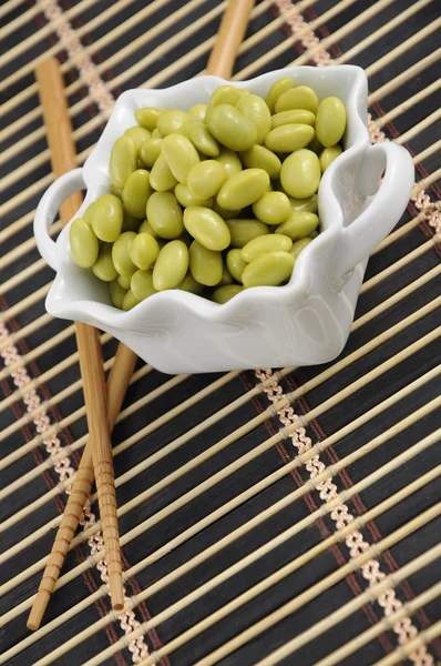 Sojabönor i en vit skål med pinnar — Stockfoto