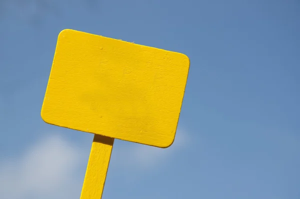 Желтый знак на ярко-голубом облачном небе — стоковое фото