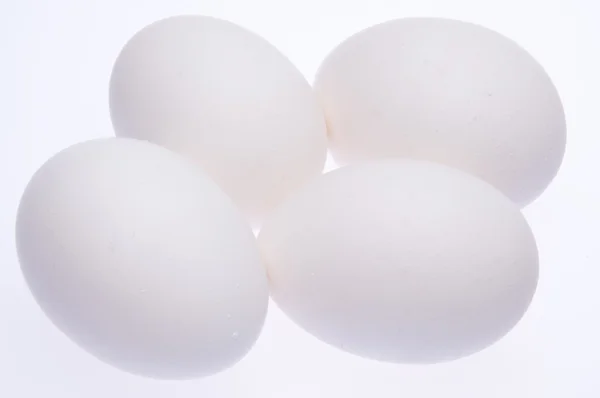 Четыре свежих яйца на белом — стоковое фото
