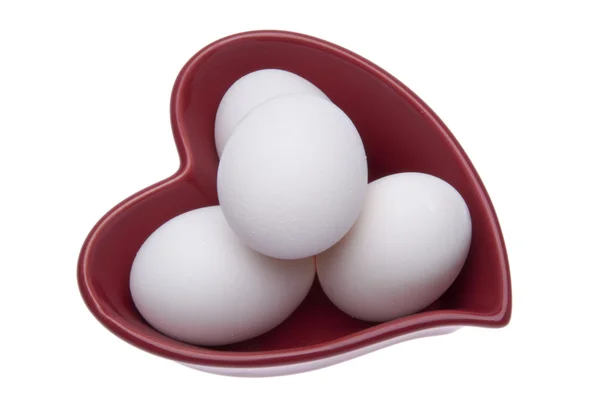 Friss tojás, egy szív alakú tál Stock Kép