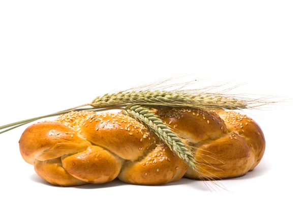 Single fresh bun and ear of wheat — Stock Photo, Image