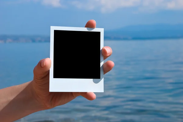 Photo in a hand on nature sea — Stockfoto