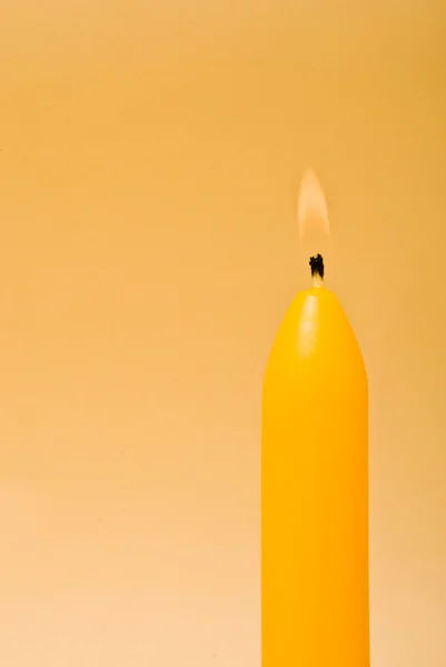 Hořící svíčka na žlutém pozadí — Stock fotografie