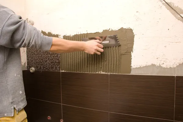Muž obklad stěny v koupelně — Stock fotografie