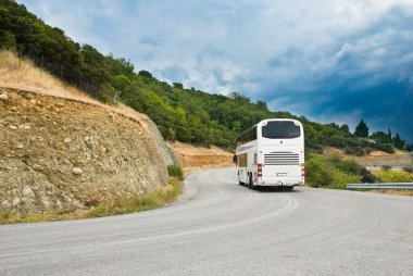 The modern tourist bus on mountain road clipart