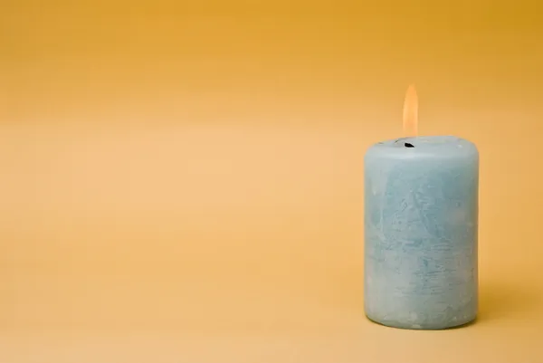 Горящая свеча на жёлтом фоне — стоковое фото
