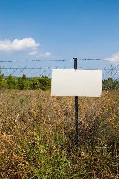 Lege witte bord op een ketting link hek. — Stockfoto