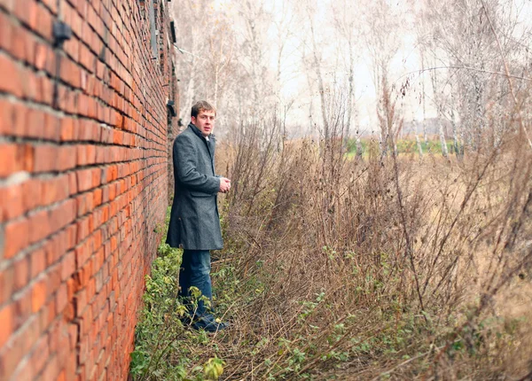 stock image The man in a coat about a wall