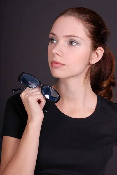 Jovem mulher em preto segurando óculos — Fotografia de Stock