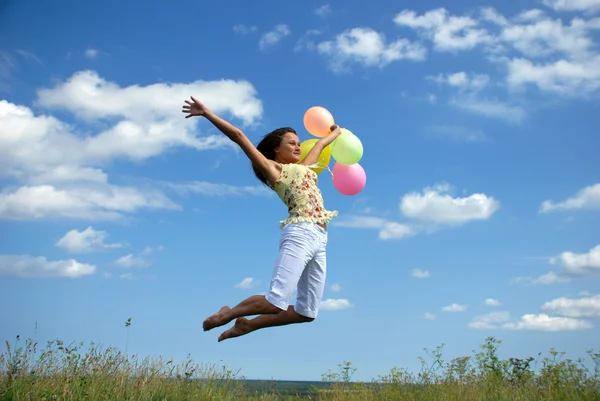 Щаслива жінка літає з повітряними кулями — стокове фото