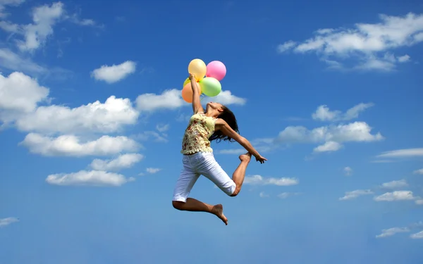 Happy woman flying with balloons — Stock Photo, Image