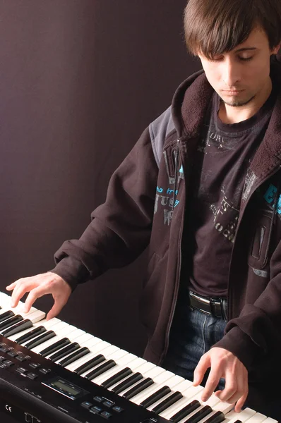 A young man playing on a synthesizer — Stock Photo, Image