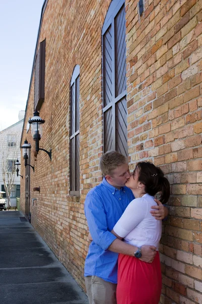 Pareja besándose por ladrillo edificio — Foto de Stock