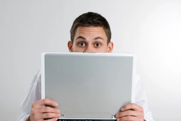Homem jovem espreitando por computador portátil — Fotografia de Stock