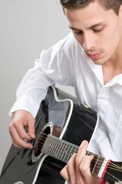 Ung man strums akustisk gitarr — Stockfoto