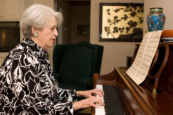Старшая женщина играет на пианино — стоковое фото