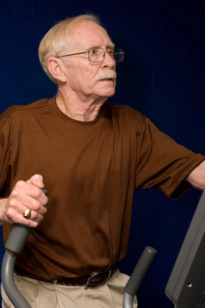 Homme âgé sur machine elliptique — Photo