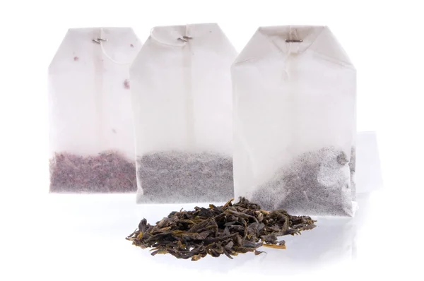 Three teabag and heap of black tea — Stock Photo, Image