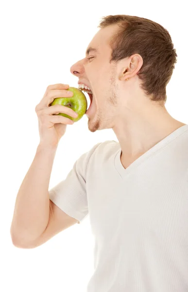 Genç adam ısırıkları yeşil taze elma — Stok fotoğraf