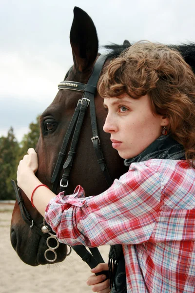 Девушка рядом с лошадью смотрит вперед — стоковое фото
