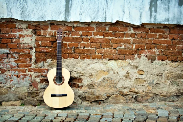 Gitarre an alter Mauer lizenzfreie Stockfotos