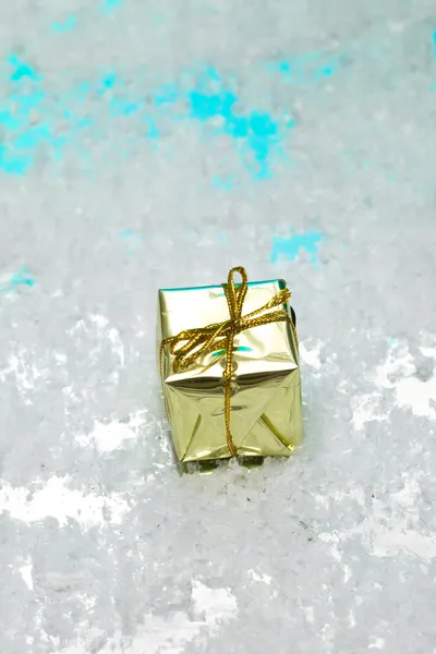Scatola regalo dorata sulla neve — Foto Stock