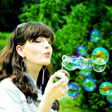 Young girl blowing soap bubbles clipart