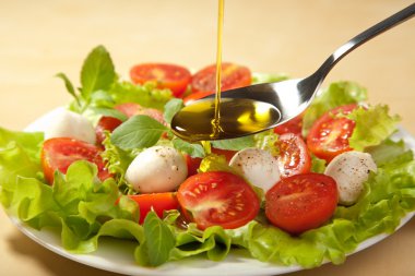 Olive oil pouring over salad clipart